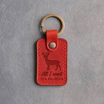 Poppy red leather keychain debossed with a whitetail buck above the words All I want IS A BIG BUCK, on gray plaster