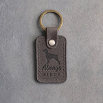 Country gray leather keychain debossed with a Brittany silhouette and the words Always BIRDY, on gray concrete
