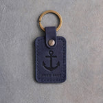 Blueberry leather keychain debossed with an admiralty anchor above HOLD FAST, on gray concrete