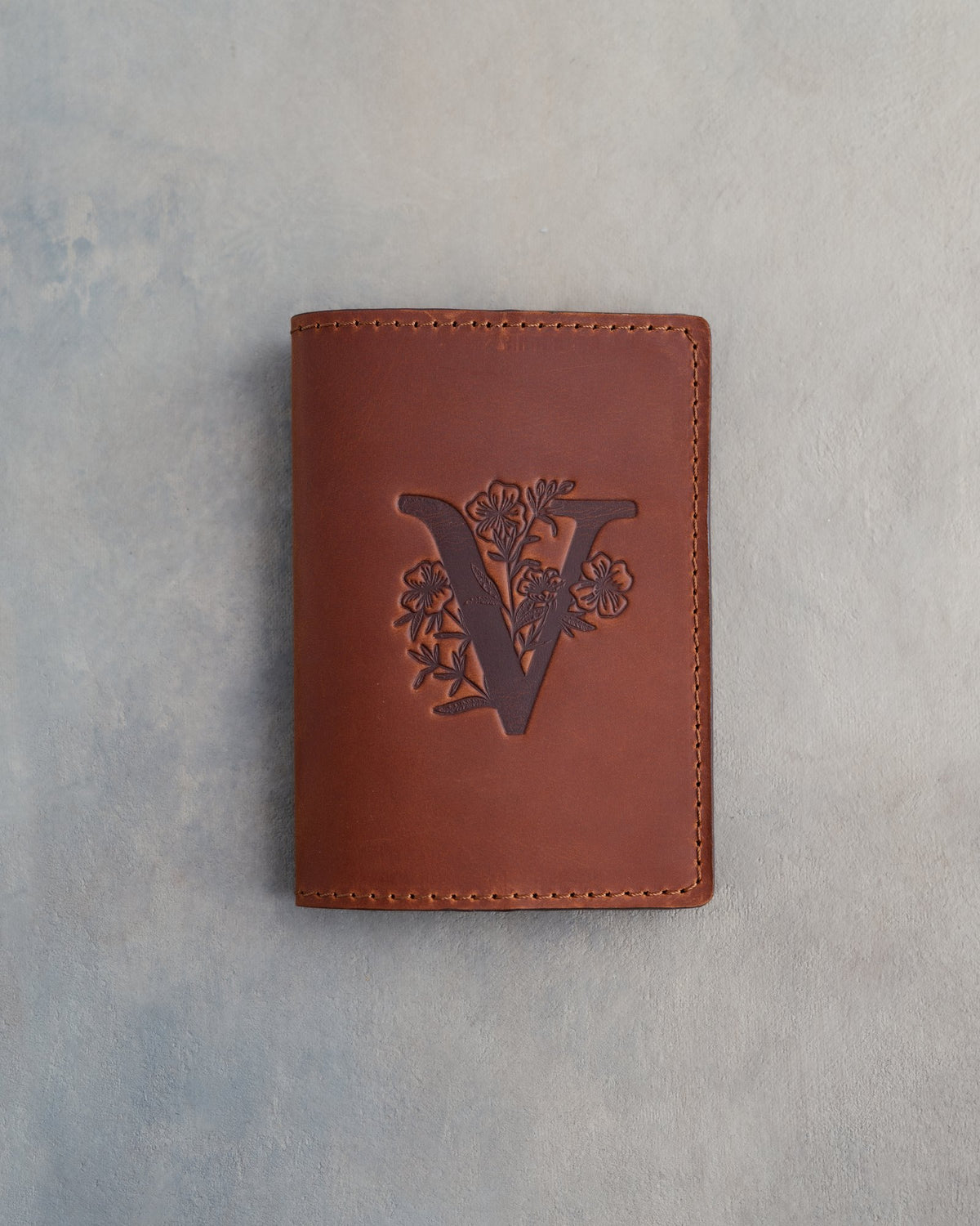Arizona leather passport cover with a large floral initial V pressed into the front