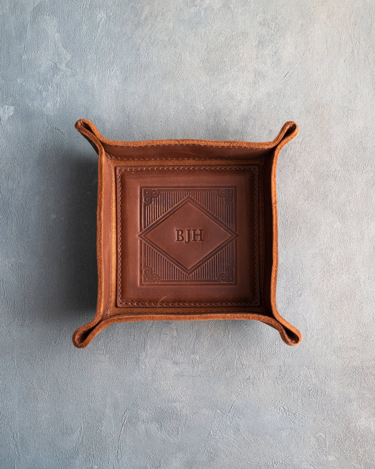 Arizona leather valet tray with snapped corners and the initials BJH pressed into the diamond frame, seen from above