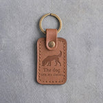 Caramel leather keychain debossed with a dog sniffing the ground above The dog and ATE MY SHOES, on gray concrete