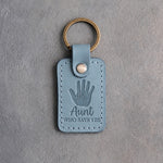 Turquoise leather keychain debossed with a small hand inside a large hand above Aunt and WHO SAYS YES