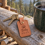 Caramel Baby Bear keychain clipped to the zipper of a small child's backpack on a wooden bench