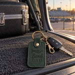 Green Band Dad keychain hanging from a truck key beside an equipment trailer at a high school stadium