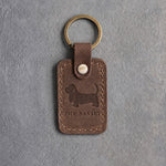 Sicilian brown leather keychain debossed with a Basset Hound silhouette above THE BASSET, on gray concrete