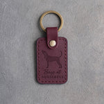 Sangria red leather keychain debossed with a Coonhound silhouette and the words Bays at SQUIRRELS, on gray concrete