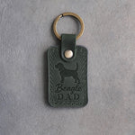 Forest green leather keychain debossed with a Beagle silhouette and the words Beagle DAD, on gray concrete