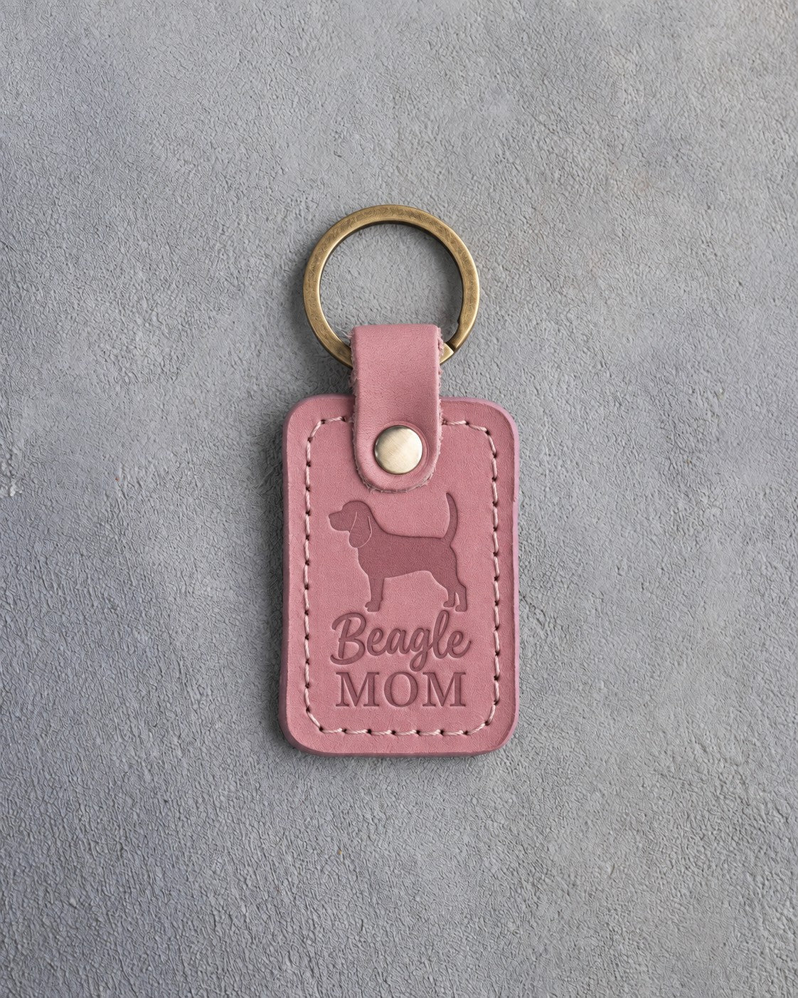 Parisian Blossom pink leather keychain debossed with a Beagle silhouette and the words Beagle MOM, on gray concrete