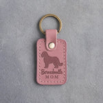 Parisian Blossom pink leather keychain debossed with a Bernedoodle silhouette and the words Bernedoodle MOM, on gray concrete