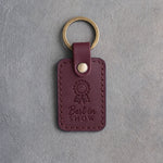 Sangria leather keychain debossed with a show rosette and the words Best in SHOW, on gray concrete