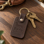 Dark brown Big Dog Short Legs keychain lying on a walnut table with brass keys and a leather leash behind