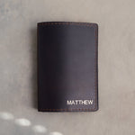 Black leather passport cover with the name MATTHEW in straight capitals in the bottom corner