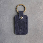 Blueberry navy leather keychain debossed with a Chow Chow silhouette and the words Blue TONGUE CLUB, on gray concrete