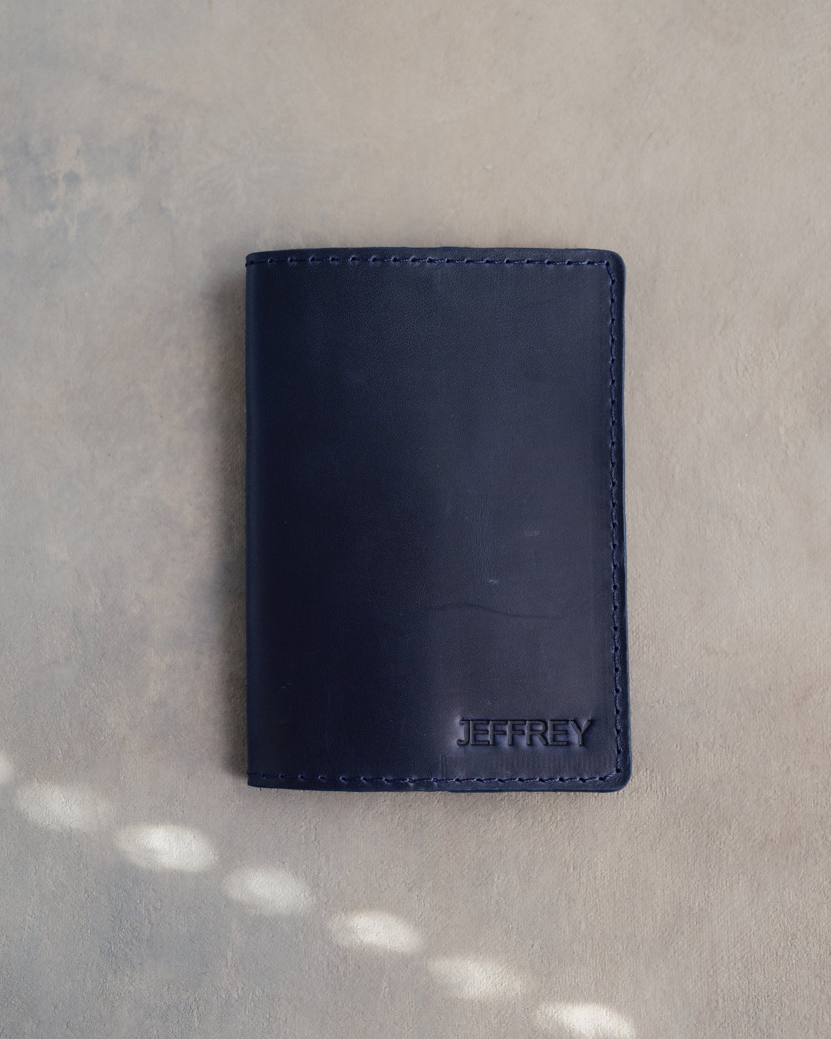 Blueberry leather passport cover with the name JEFFREY in straight capitals pressed into the bottom corner