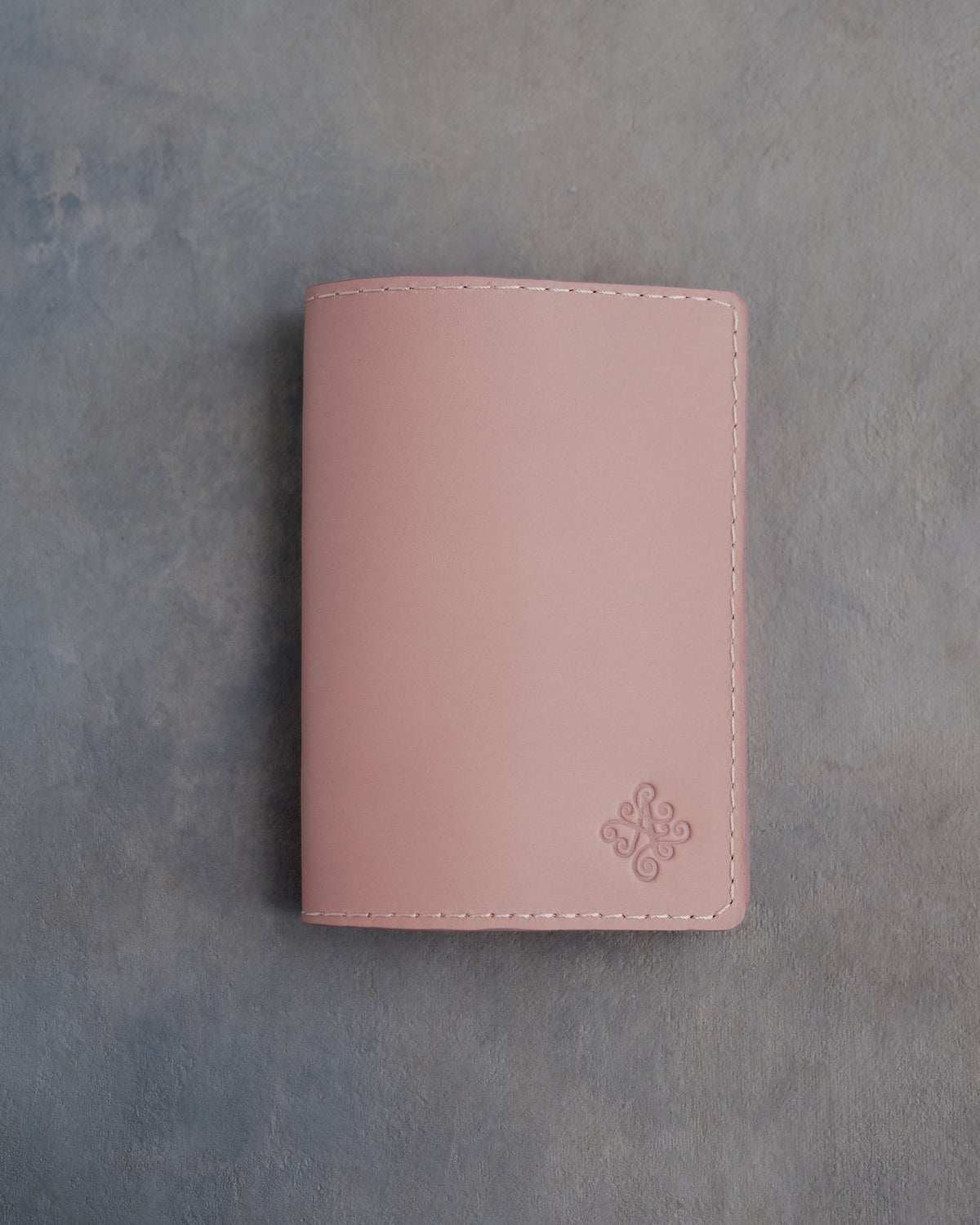 Blush leather passport cover with a flower initial pressed into the bottom corner
