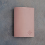 Blush leather passport cover with a flower initial pressed into the bottom corner