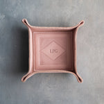 Blush leather valet tray with snapped corners and the initials LPG pressed into the diamond frame, seen from above