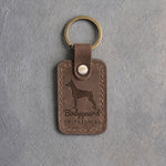 Sicilian brown leather keychain debossed with a Doberman silhouette and the words Bodyguard IN PAJAMAS, on gray concrete