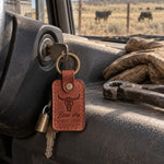 Arizona Bone dry SINCE JUNE keychain on a ranch truck's ignition key, a dry pasture and fence line through the windshield