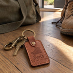 Tan Boots on the Ground keychain clipped to a duffel bag strap on an airport bench