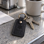 Black Born a 312 keychain on apartment keys resting on a cafe counter beside an L train map
