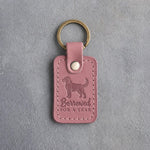Parisian Blossom pink leather keychain debossed with a young puppy and the words Borrowed FOR A YEAR, on gray concrete