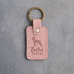 Blush pink leather keychain debossed with a Boston Terrier silhouette and the words Boston MOM, on gray concrete