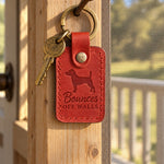 Red Bounces Off Walls keychain on a hallway floor beside a well-loved rope toy