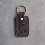 Dark espresso leather keychain debossed with a Boxer silhouette and the words Boxer DAD, on gray concrete