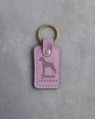 Lilac leather keychain debossed with a boxer silhouette and the words Boxer GRANDMA, on gray concrete
