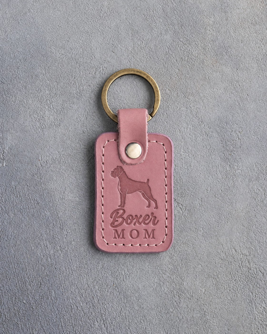 Parisian Blossom pink leather keychain debossed with a Boxer silhouette and the words Boxer MOM, on gray concrete