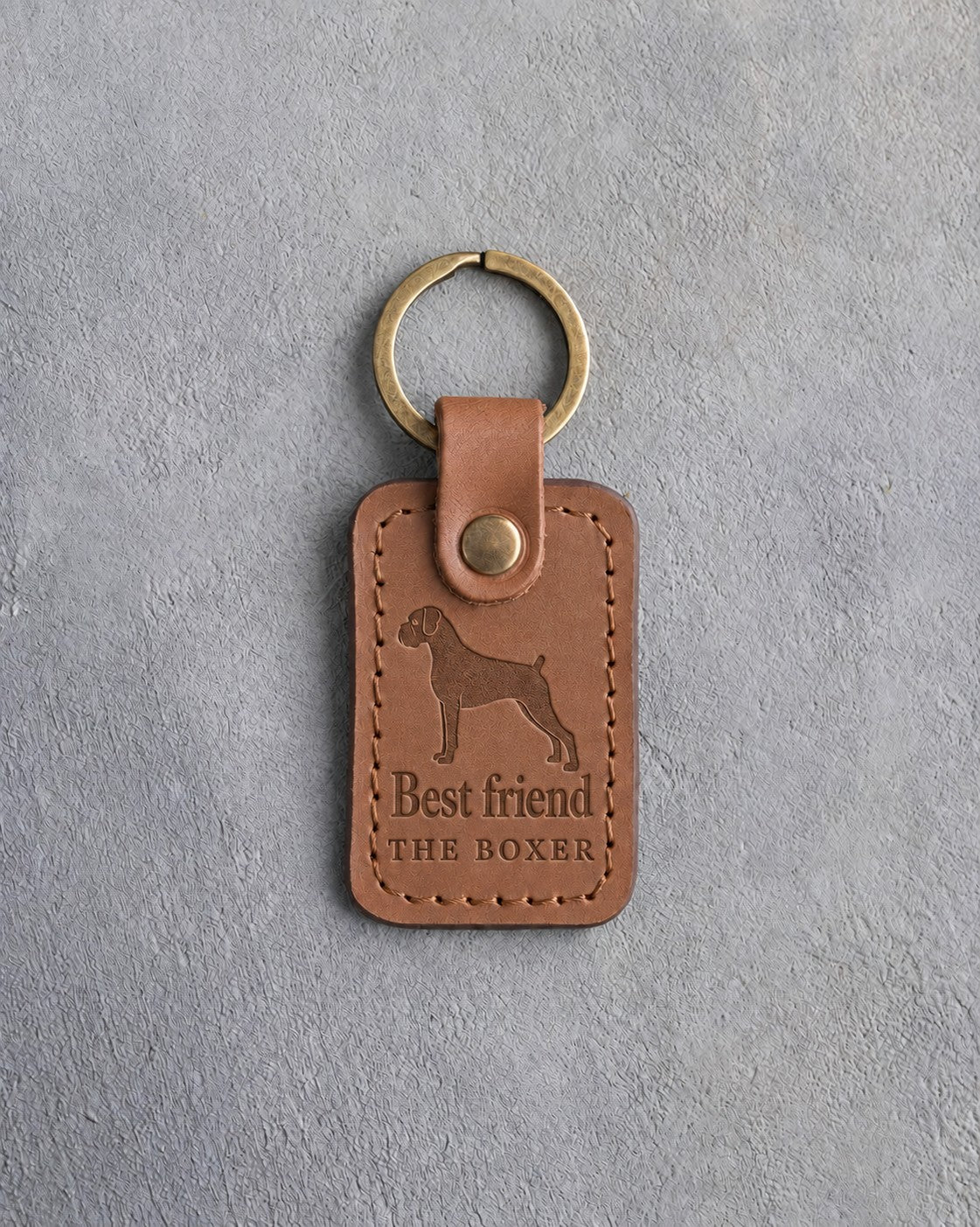 Caramel leather keychain debossed with a Boxer silhouette above Best friend and THE BOXER, on gray concrete