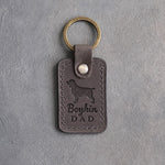 Country gray leather keychain debossed with a Boykin spaniel and Boykin DAD lettering, on gray concrete