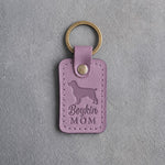 Lilac leather keychain debossed with a Boykin spaniel and the words Boykin MOM, on gray concrete