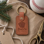 Caramel Break It In keychain on kraft wrapping paper beside wool yarn and a new white baseball