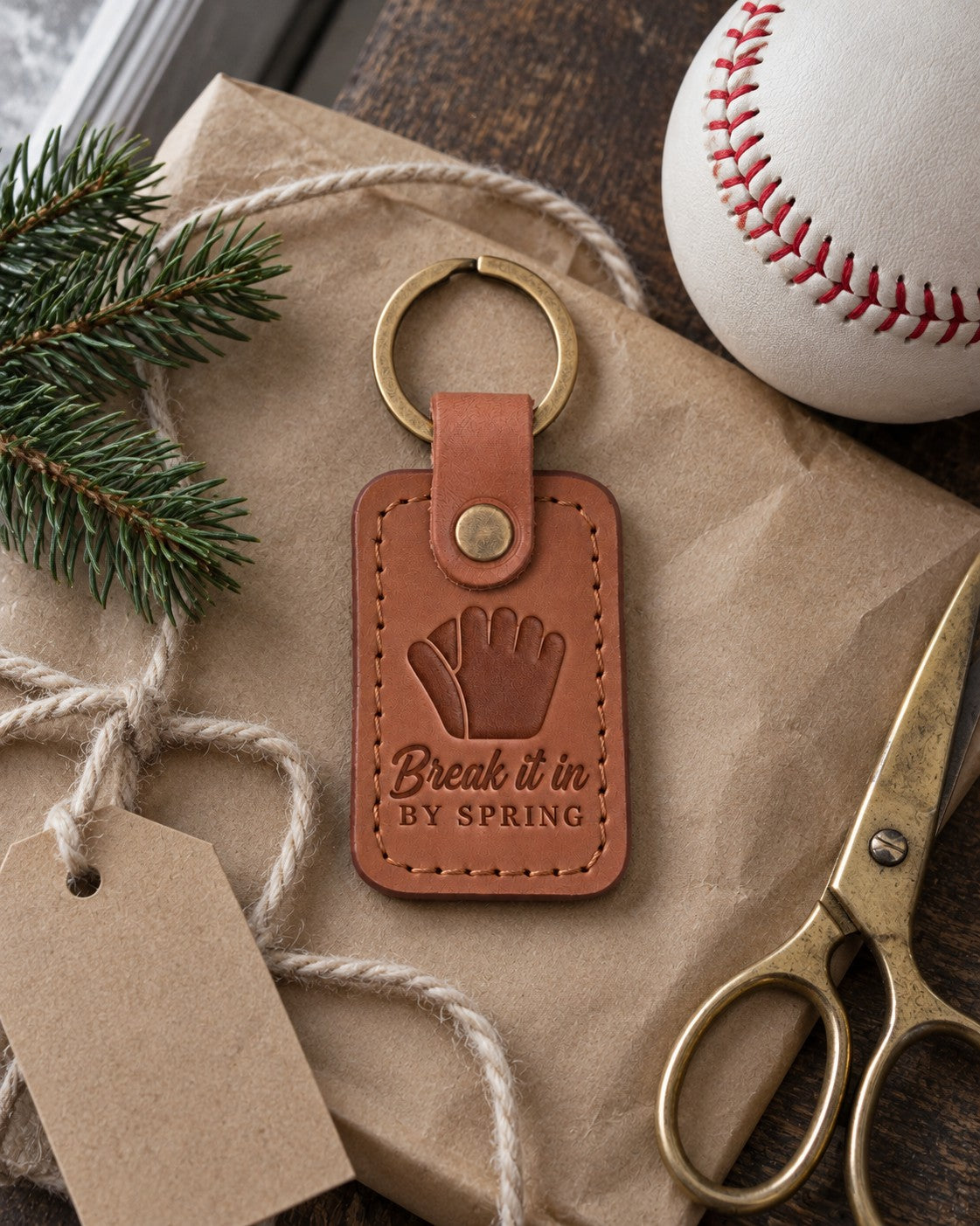 Caramel Break It In keychain on kraft wrapping paper beside wool yarn and a new white baseball