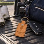 Breakfast Ball keychain in golden tan leather beside a coffee cup and a golf ball on a first tee bench at sunrise