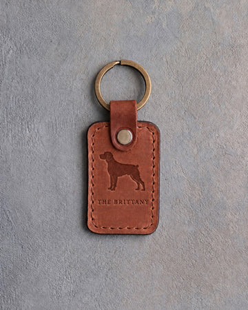 Arizona tan leather keychain debossed with a Brittany silhouette above THE BRITTANY, on gray concrete