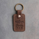Sicilian brown leather keychain debossed with a brook trout above the words Brookie DAD, on gray plaster