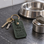 Green Brought Me a Gift keychain on a doormat by a front door in early morning light