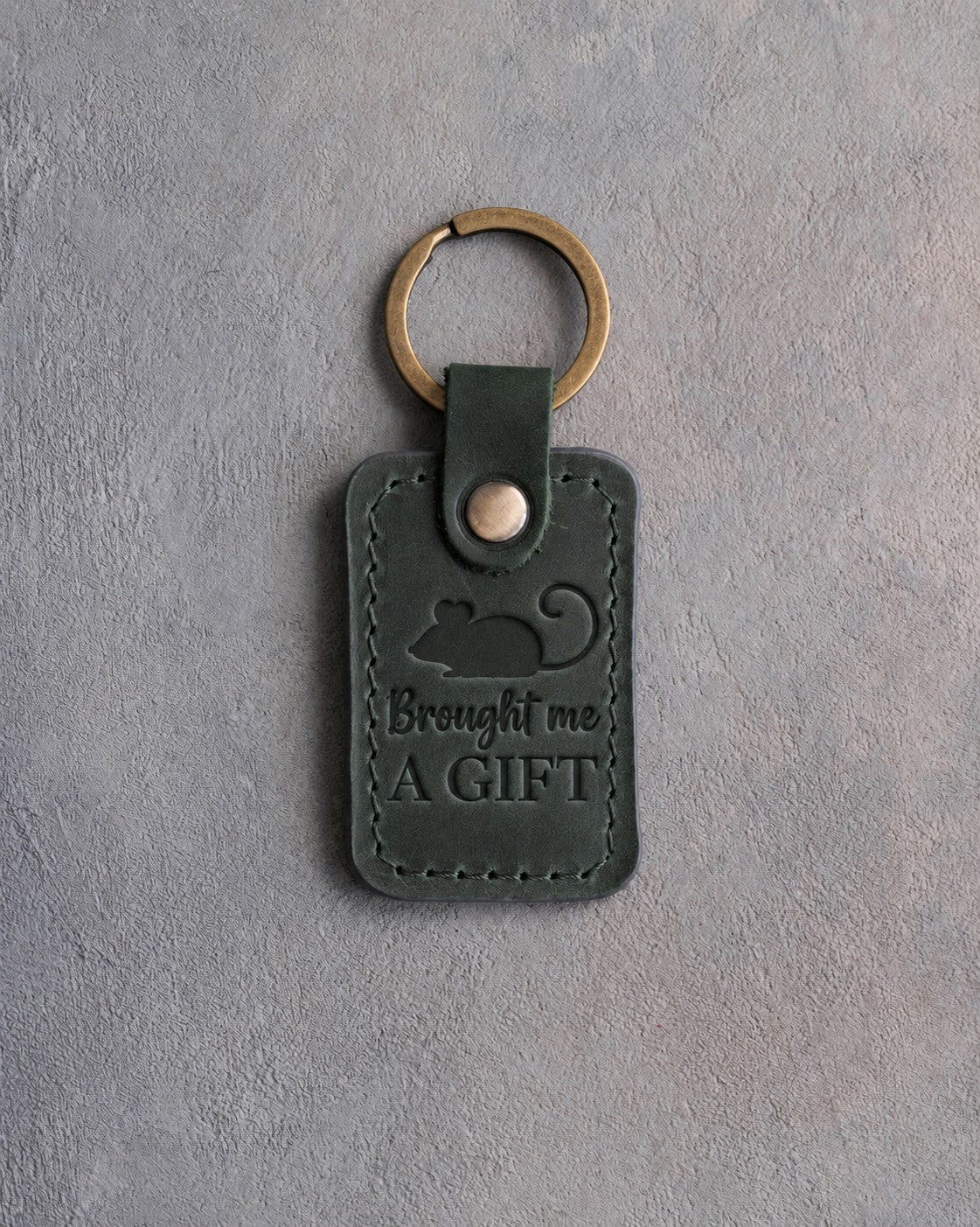 Forest green leather keychain debossed with a toy mouse above the words Brought me A GIFT