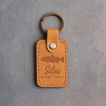 Indian Summer leather keychain debossed with a brown trout above Silas and BROWN TROUT, on gray plaster