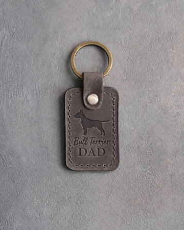 Country gray leather keychain debossed with a Bull Terrier silhouette and Bull Terrier DAD on gray concrete