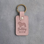 Blush pink leather keychain with a debossed English bulldog and the words Bulldog MOM, on gray concrete