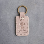 Gray sand leather keychain debossed with a potted cactus above Cactus COLLECTOR, on gray concrete