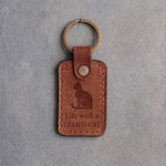 Arizona tan leather keychain debossed with a sitting cat above Life with a and CALICO CAT, on gray concrete