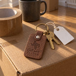 Brown Call Your Father keychain on a dorm key held out over the open tailgate of a loaded pickup