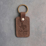 Sicilian brown leather keychain debossed with a Texas silhouette and a heart at Houston above Call your FATHER, on gray concrete
