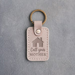 Gray sand leather keychain debossed with a gabled house above Call your and MOTHER